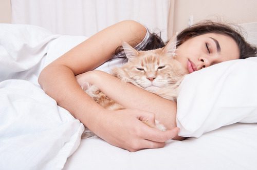 woman-cuddling-with-cat-in-bed-while-sleeping